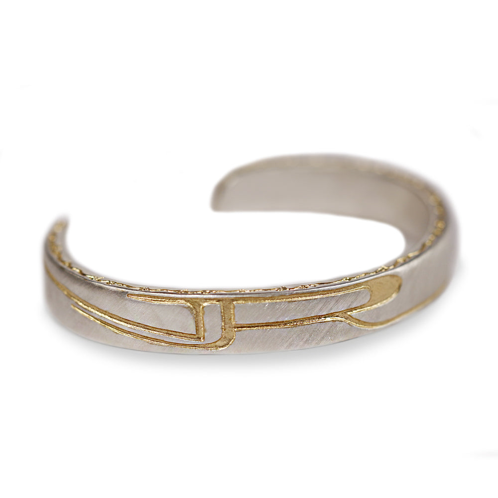 A silver-toned open cuff ring with a textured finish and gold-toned geometric line details, shown on a plain white background.