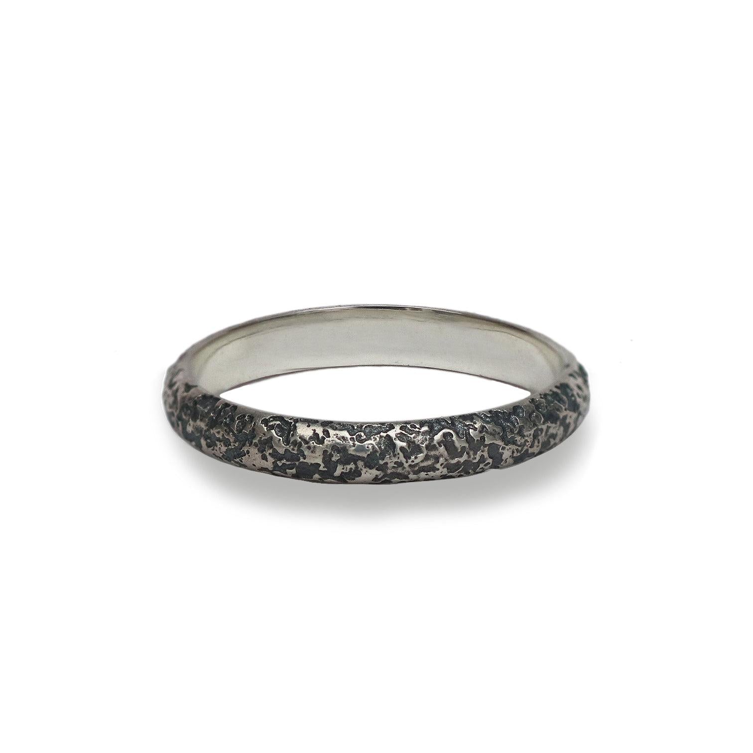 Silver ring with oxidised textured surface on a white background