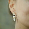 Close-up of a person wearing elegant earrings with a blurred background