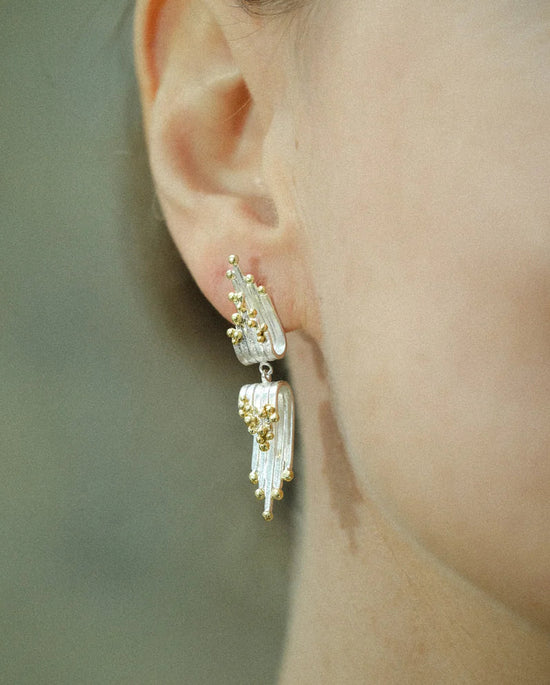 Close-up of a person wearing elegant earrings with a blurred background