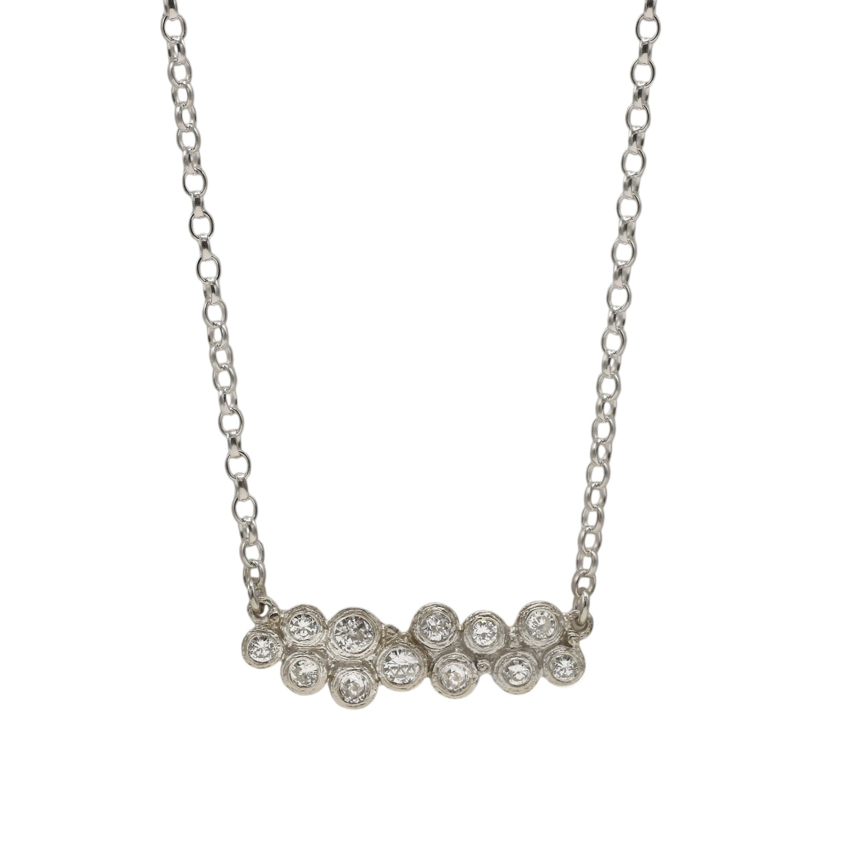 A white gold necklace featuring a curved bar of seven round-cut clear gemstones in a row, suspended from a delicate link chain against a plain white background.