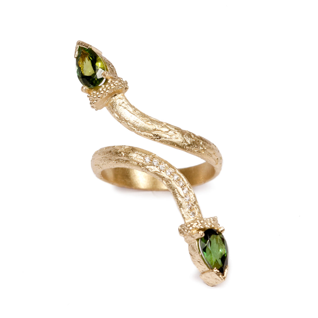 A textured gold snake ring with green sapphires and white diamonds that climbs up the thumb. 