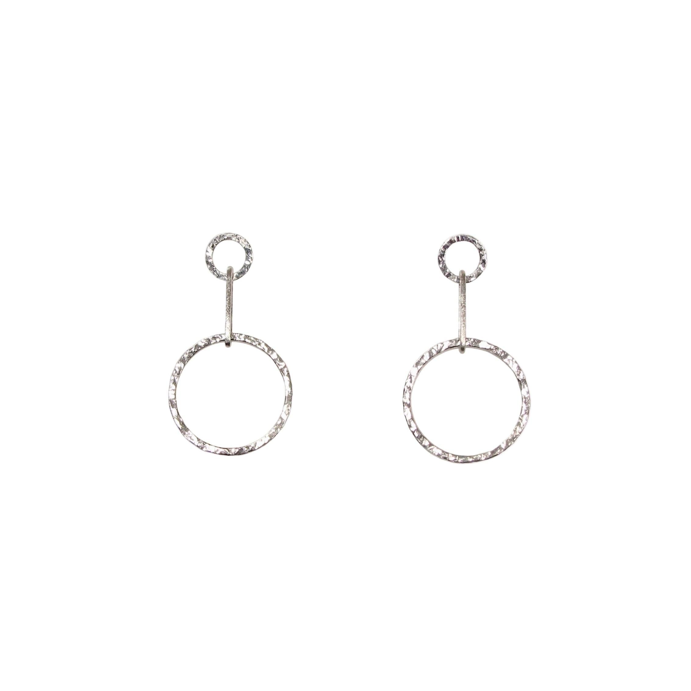 A pair of silver circle drop earrings with a hammered texture, hanging from small circular posts.