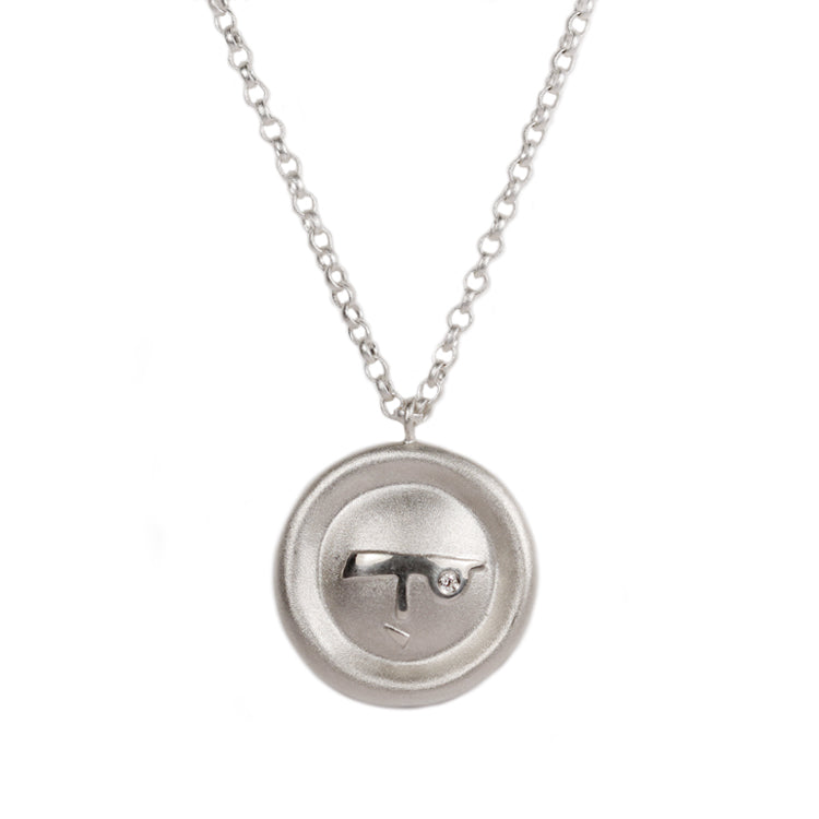 Silver disc pendant with a abstract face and diamond on a silver chain on a white background 